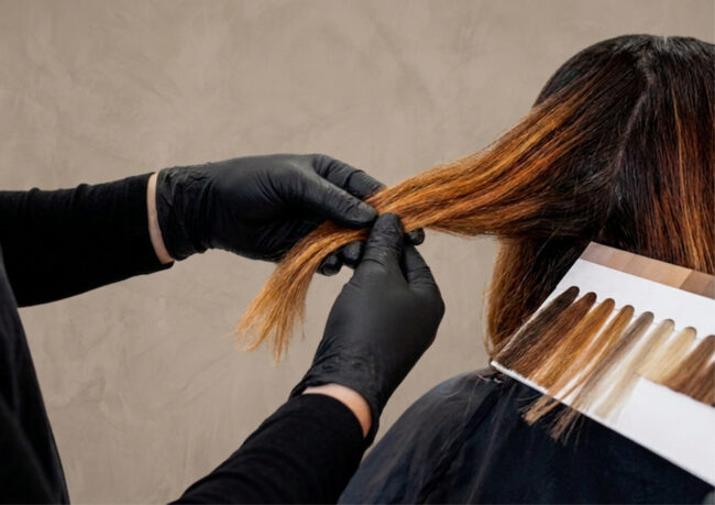 Stylist carefully analyzing client's hair strands during a color correction consultation at a boutique salon.